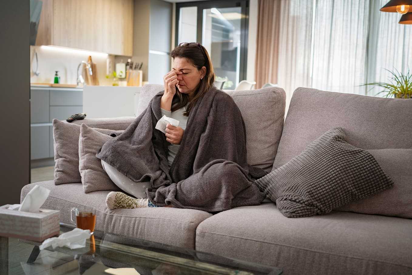 Kvinna med bihåleinflammation som håller handen mot näsan – symtom, orsaker och behandling av sinuit hos Doktera.